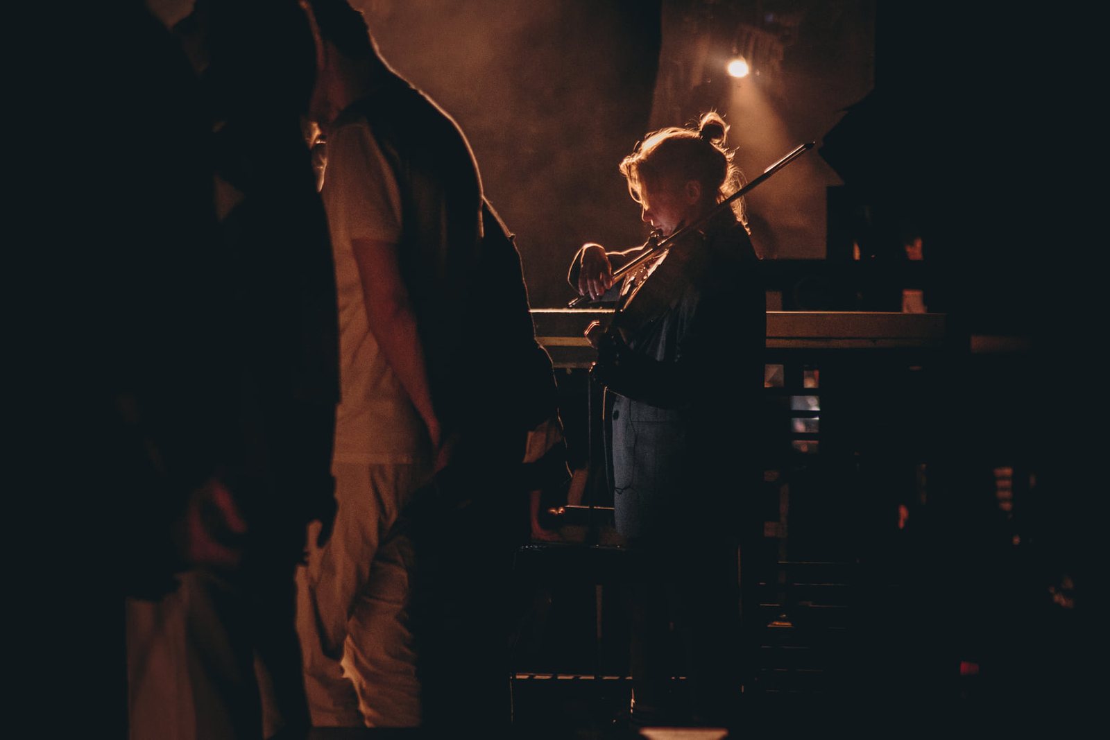 Alina Petrova playing violin, backlit on stage